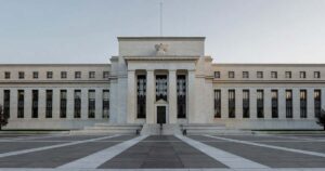 The neoclassical facade of the Federal Reserve headquarters building in Washington under soft morning light with a quiet empty plaza