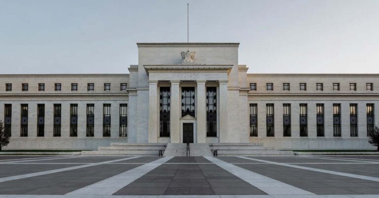 The neoclassical facade of the Federal Reserve headquarters building in Washington under soft morning light with a quiet empty plaza