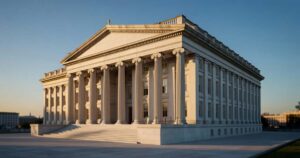 The neoclassical United States Treasury building with tall stone columns lit by golden evening sunlight under a clear blue sky