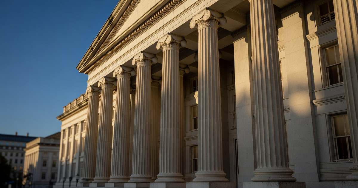 Sunlit limestone columns along the front facade of the United States Treasury building in Washington DC under a clear deep blue afternoon sky