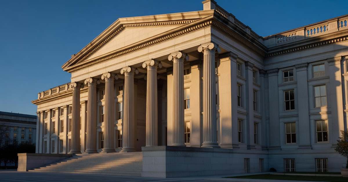 Early morning sunlight rakes across the limestone columns of the United States Treasury Building in Washington, D.C., under a clear deep blue sky.