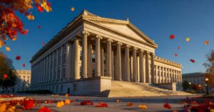 Early morning sunlight rakes across the stone columns of the United States Treasury Building in Washington DC under a clear autumn sky